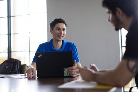 A Rolllins graduate admission counselor in a blue Rollins polo meets one-on-one with a prospective student.