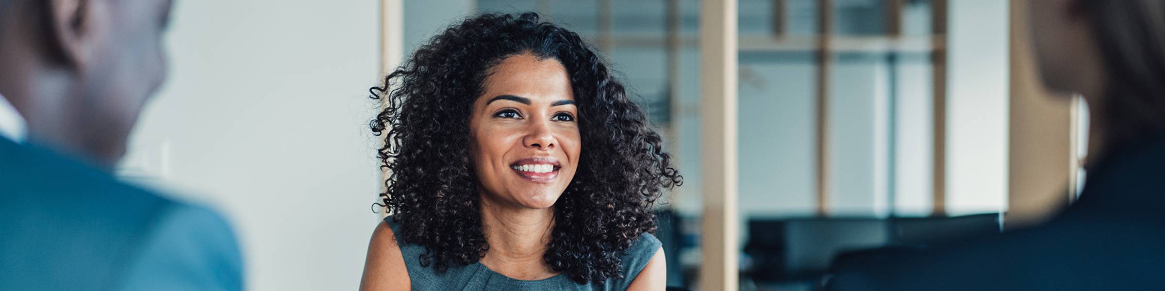 A businesswoman meets with two clients in a conference room.