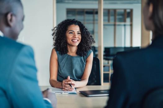 A business woman meets with a pair of clients in a conference room.