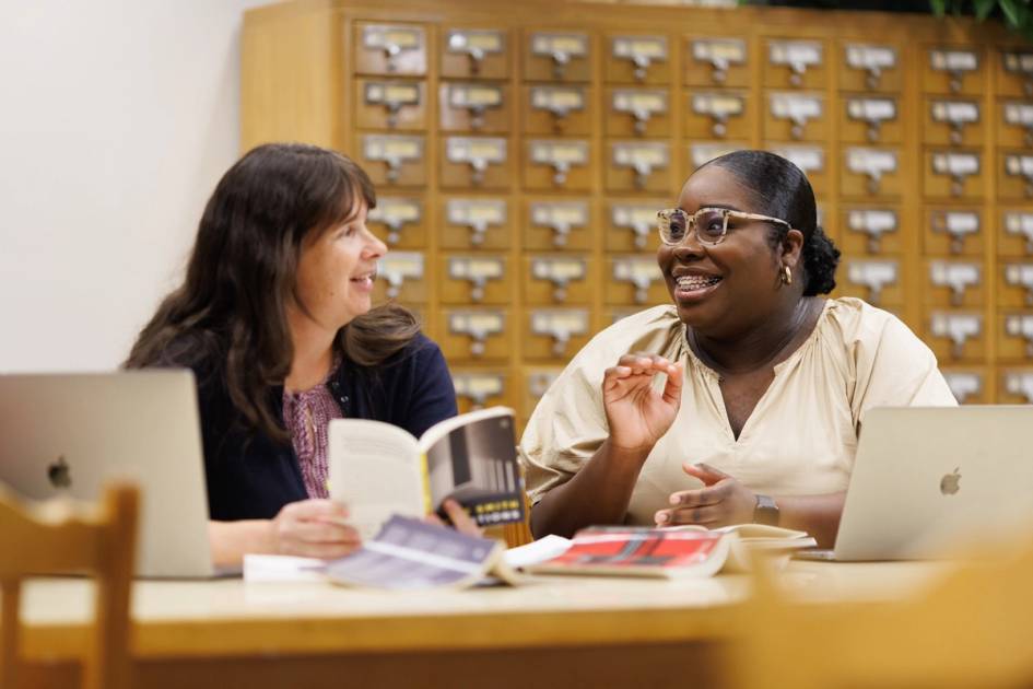 A Rollins student and professor have a conversation in the library. 