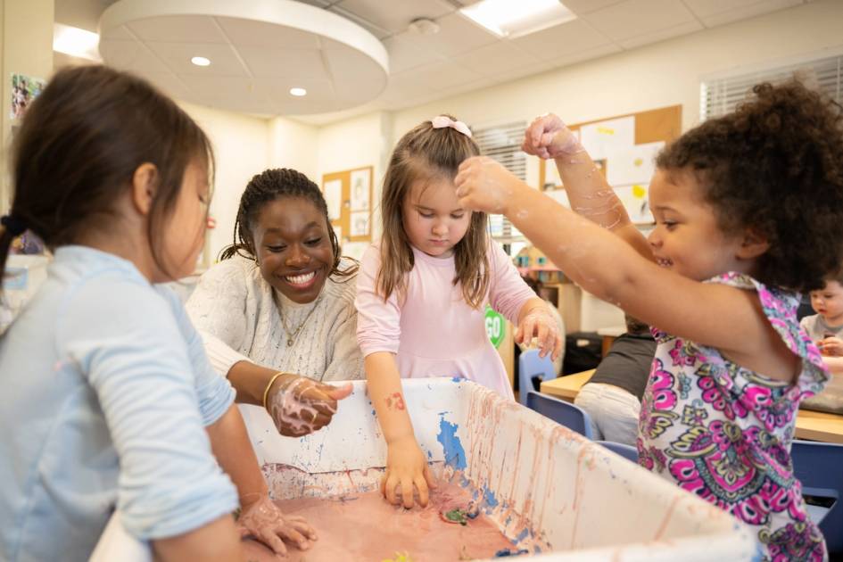 Undergraduate student and children playing in a sensory bin.