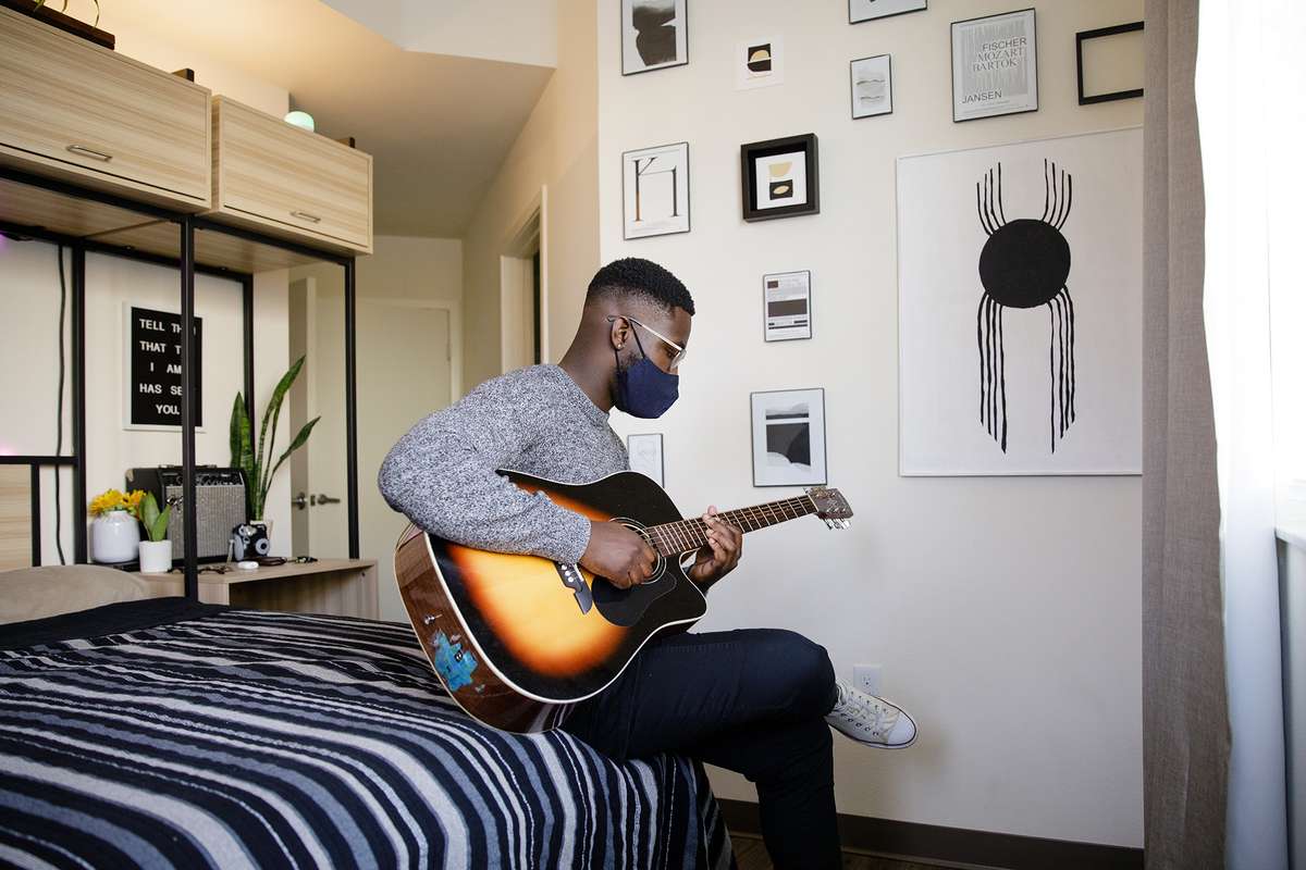 Student playing guitar in his bedroom in Lakeside Neighborhood.