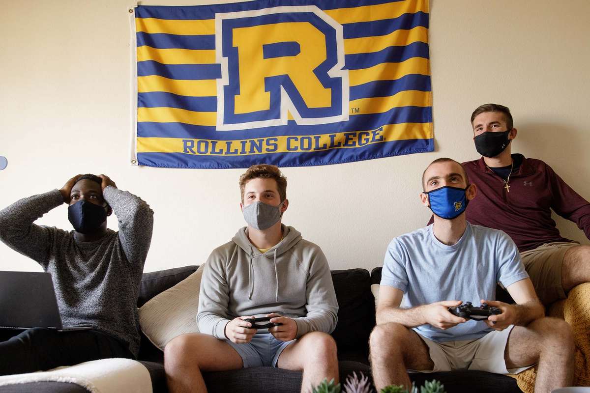 Male students playing video games in their Lakeside apartment common room.
