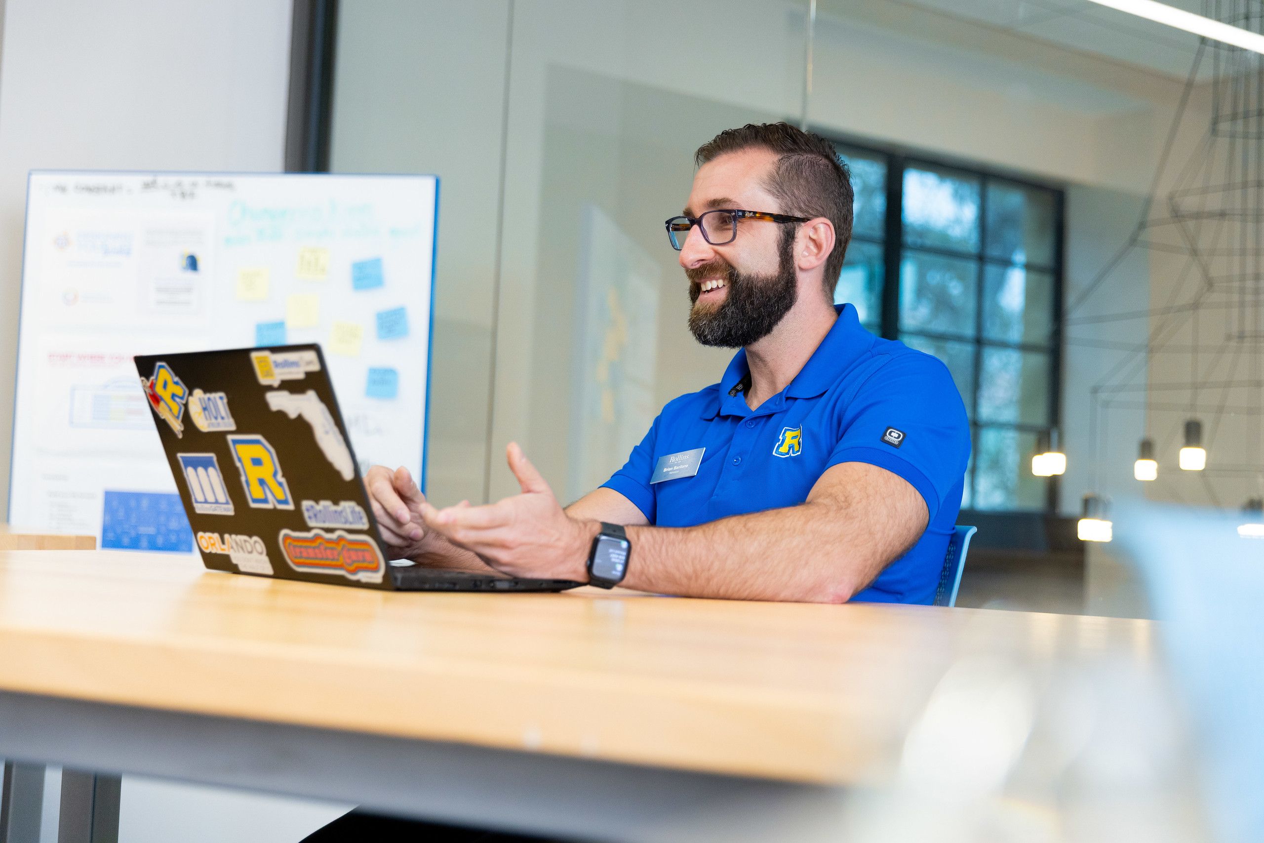 Brian Barilone, Director of Transfer and Graduate Admission, smiles while talking during a video call on his laptop at a Rollins office.