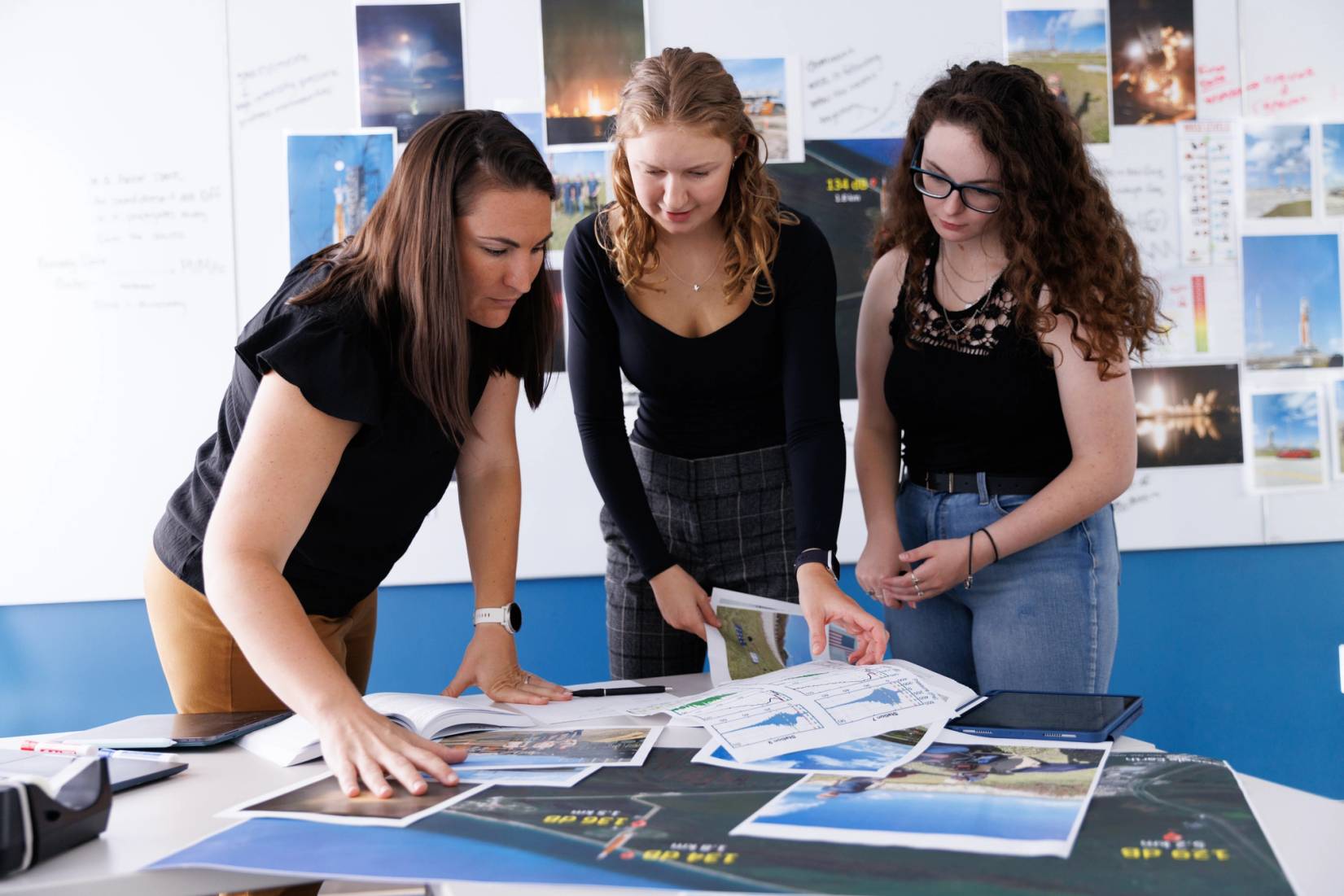 Whitney Coyle looking at photos and graphs with two students 