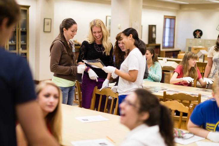 A professor and a group of students conduct research in the Olin Library archives.
