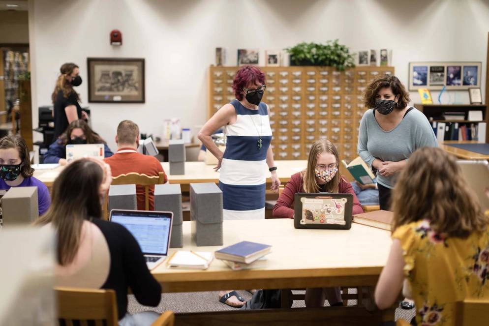 Masked professors look on as masked students conduct research