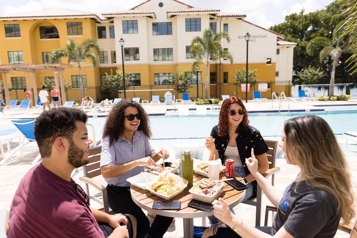 Students dining outside at the pool in Lakeside Neighborhood.