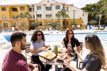 Four students share lunch on a pool deck at Rollins College.