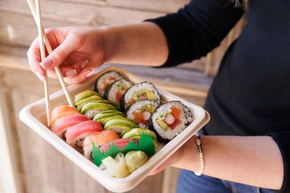 A student holds a tray of sushi