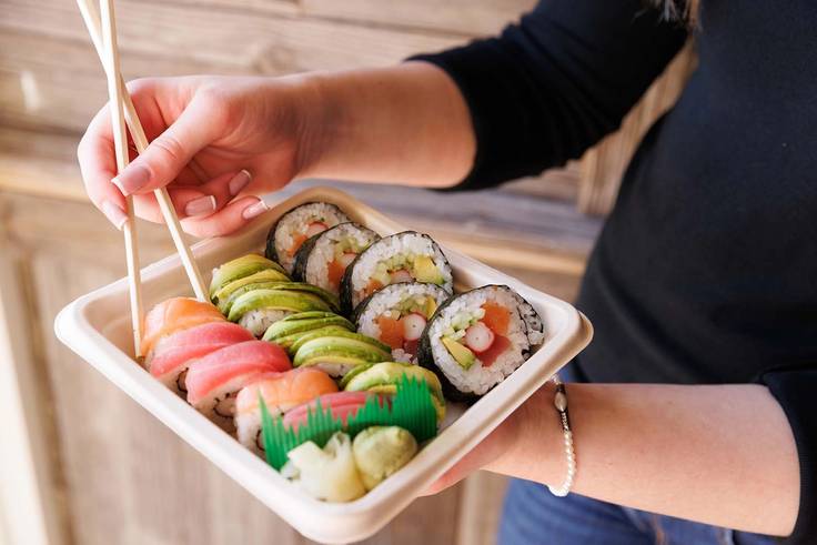 A student holds a tray of sushi