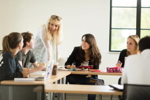 A Rollins public health professor talks with a small group of students in a classroom.