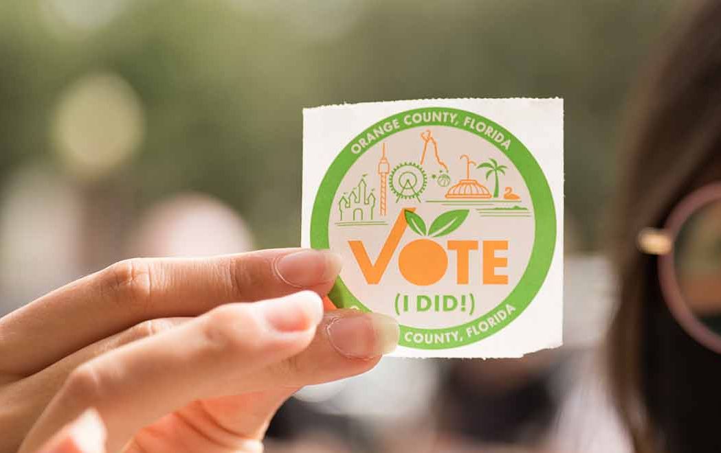 Student hold a "I Voted" sticker up