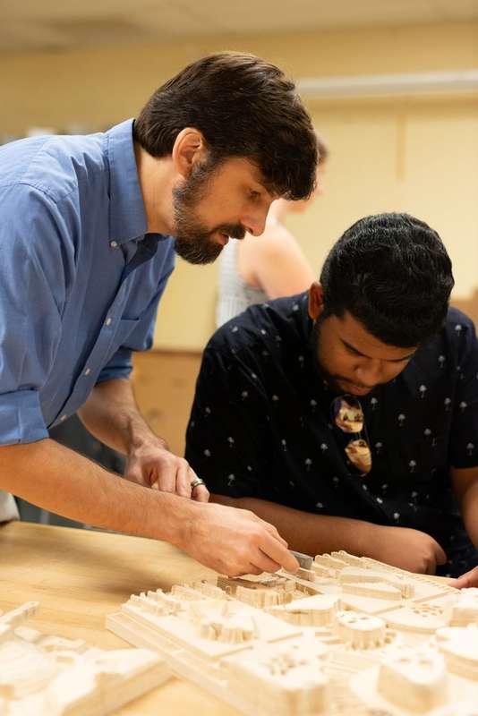 Professor Joshua Almond helping a student with a project in the workshop.