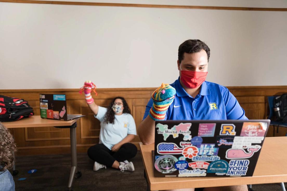 Students hold up sock puppets during a virtual puppet making workshop