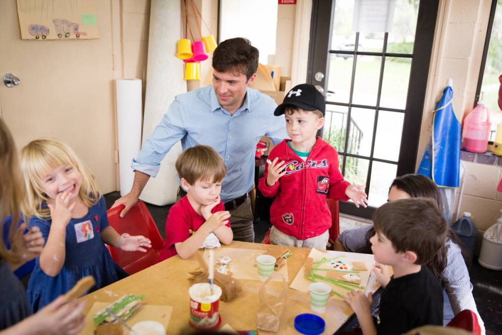 Children stand around a table.