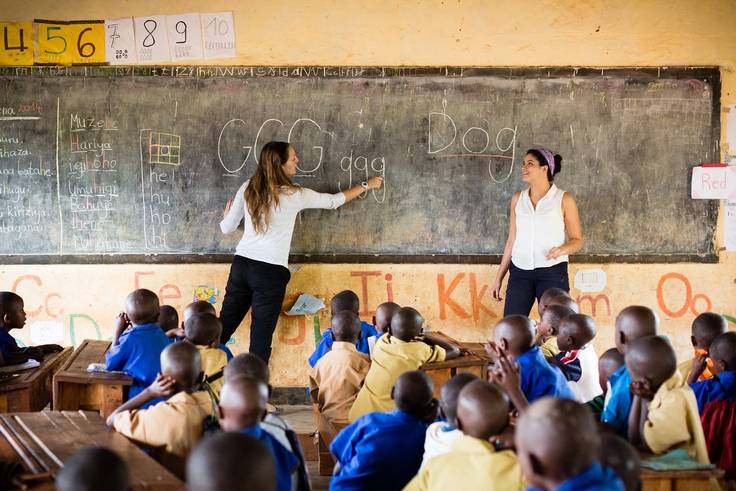 Two college students teach a classroom of young children in Rwanda.