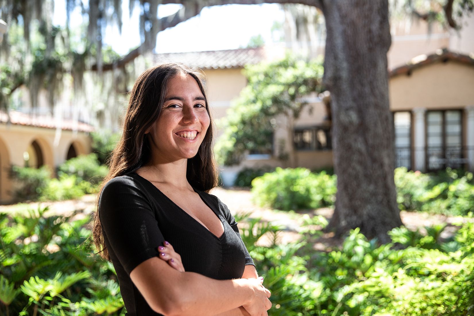 Photo of Carla Daza in front of a building with a green garden.