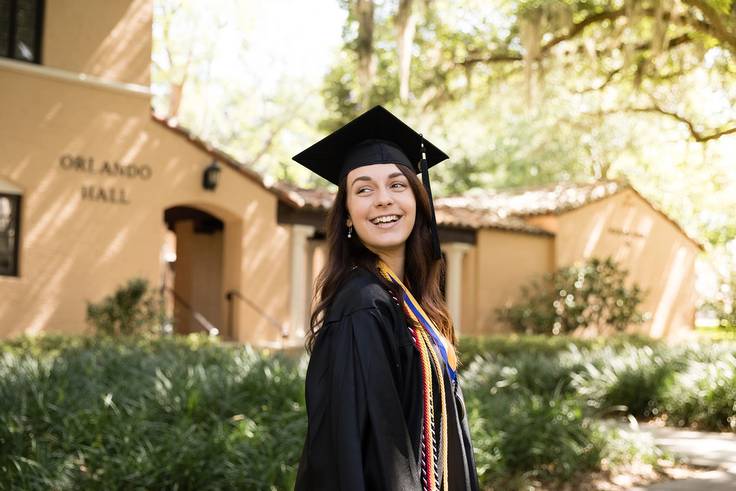 A college graduate poses in a cap and gown.