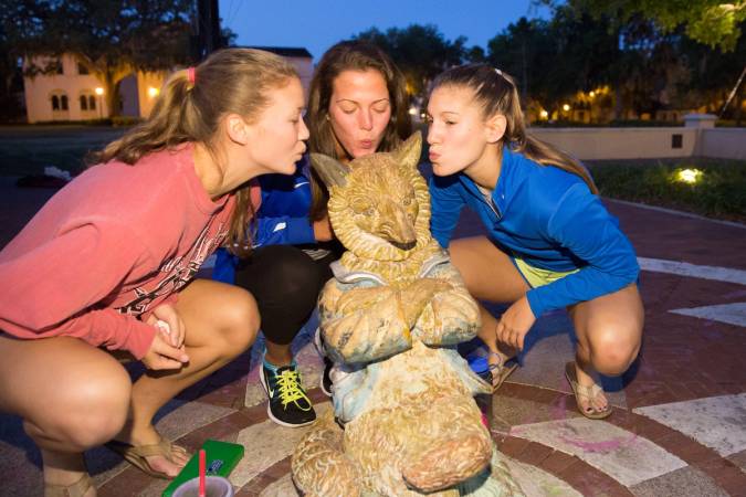 Rollins students kissing the Fox Day statute on Tars Plaza.