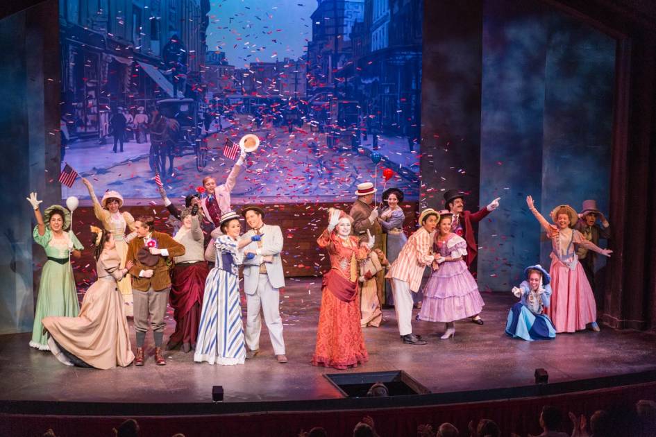 Colorful stage cast celebrates during lively period musical theater performance.