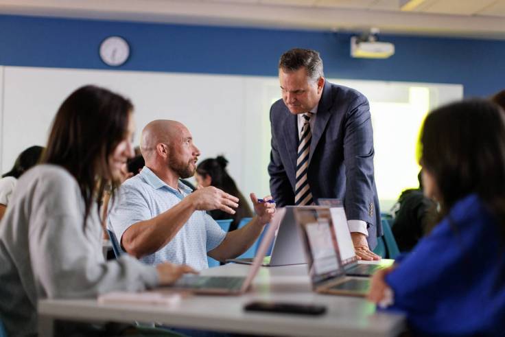 A business professor works one on one with a student during class.