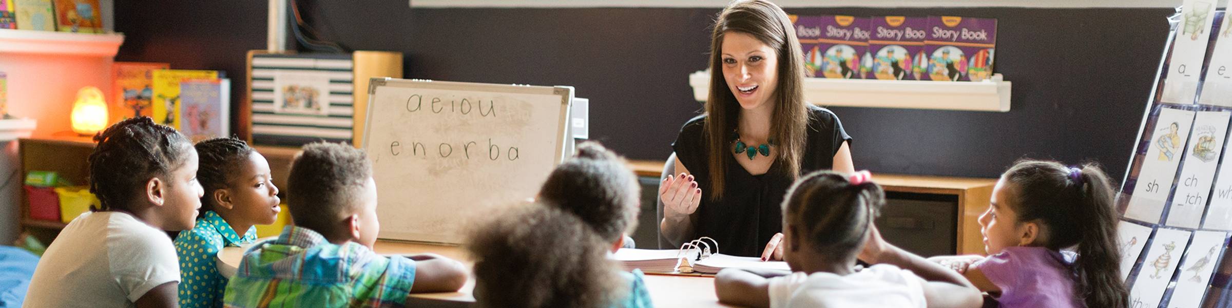 Young kids raising their hands in a classroom.