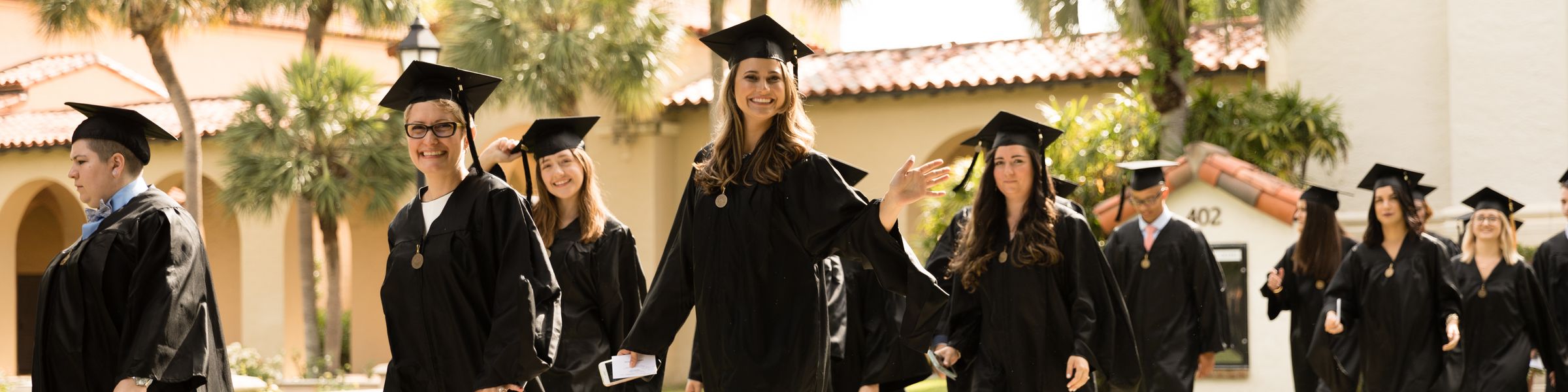 Graduates in caps and gowns walk to their commencement ceremony.