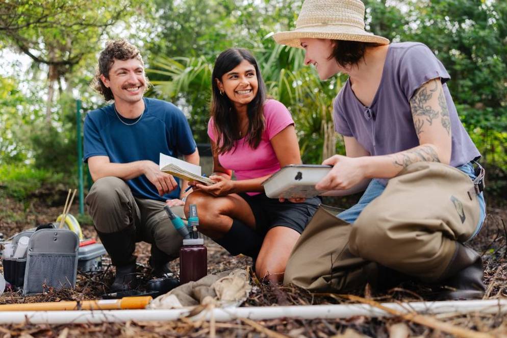 Mihika Srikrishna ’28, Sarah Winslett ’28, and biology professor Phoenix Rogers review notes and equipment during outdoor fieldwork.