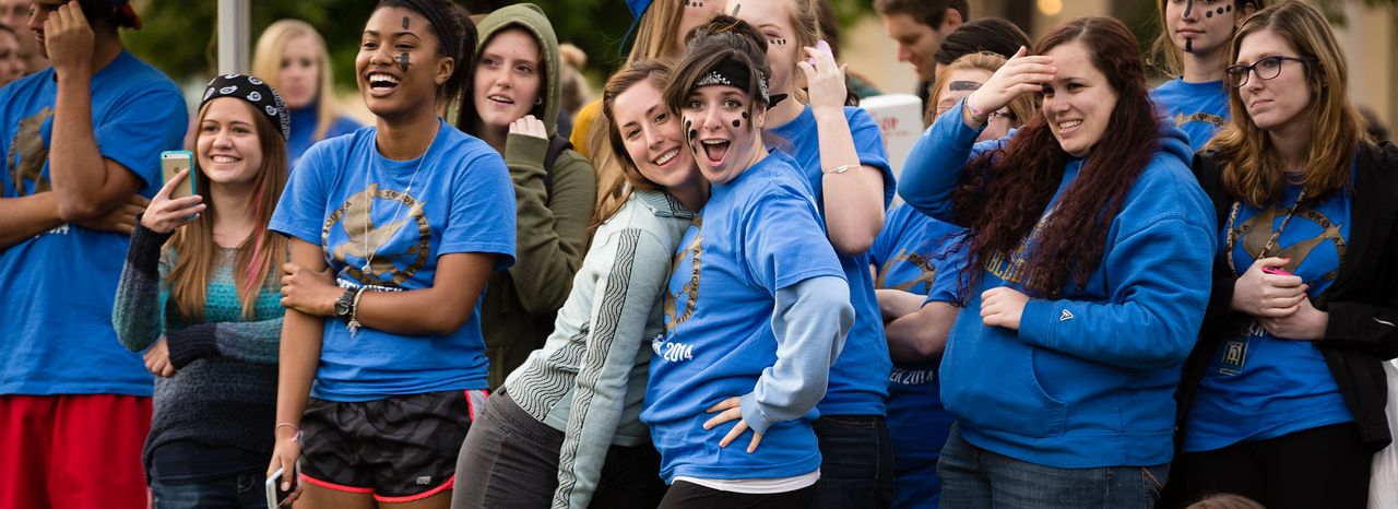 Sorority girls in blue t-shirts smiling, hugging, and looking at camera.