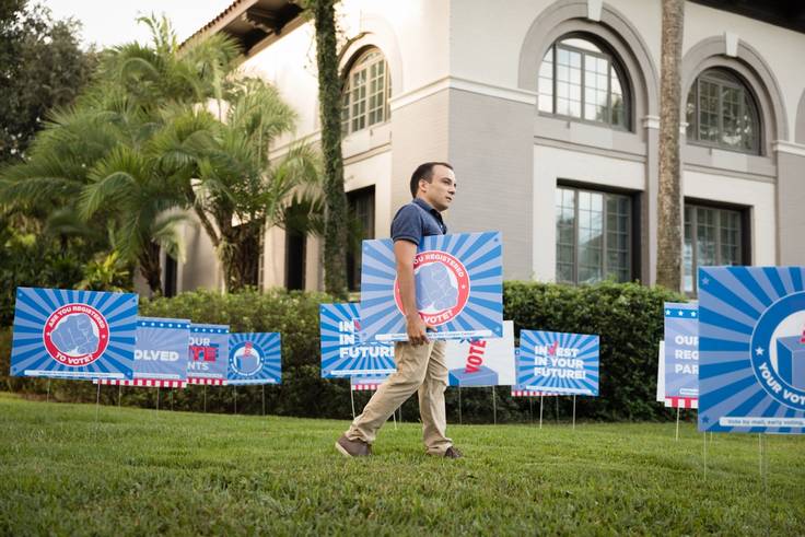 A student installs election yard signs.