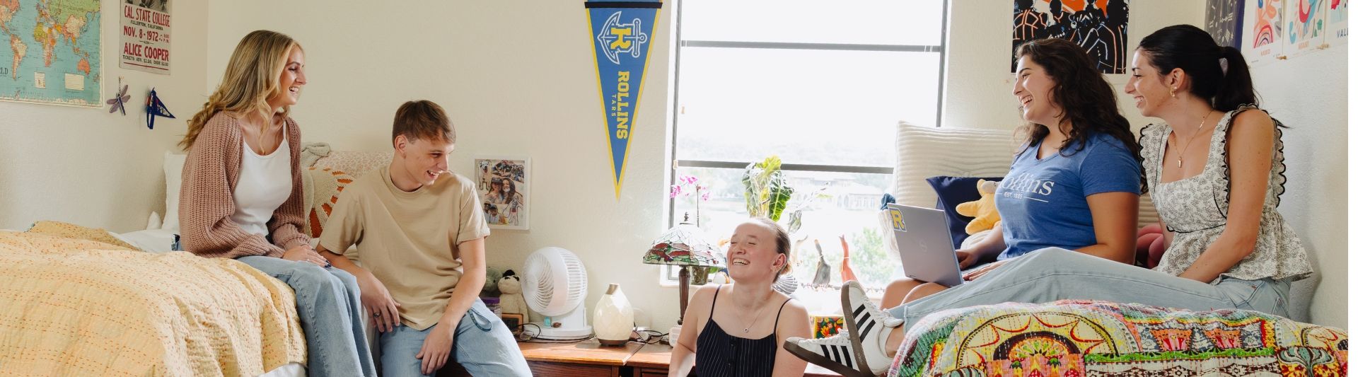 Five students laughing in a dorm.