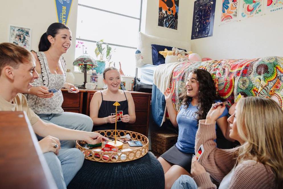 Rollins students laughing and playing a card game in a Ward Hall room