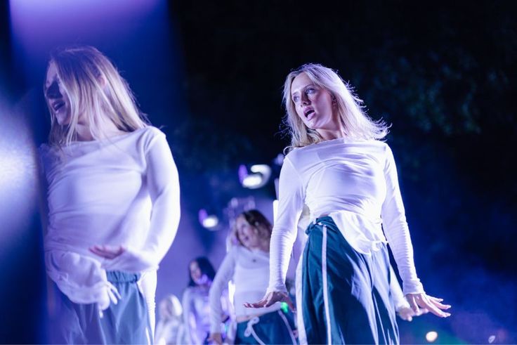Lip Sync dancers in white tops perform under dramatic blue stage lighting.