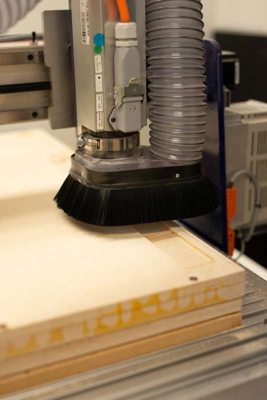A close up of a cnc router machine including a brush and vacuum.