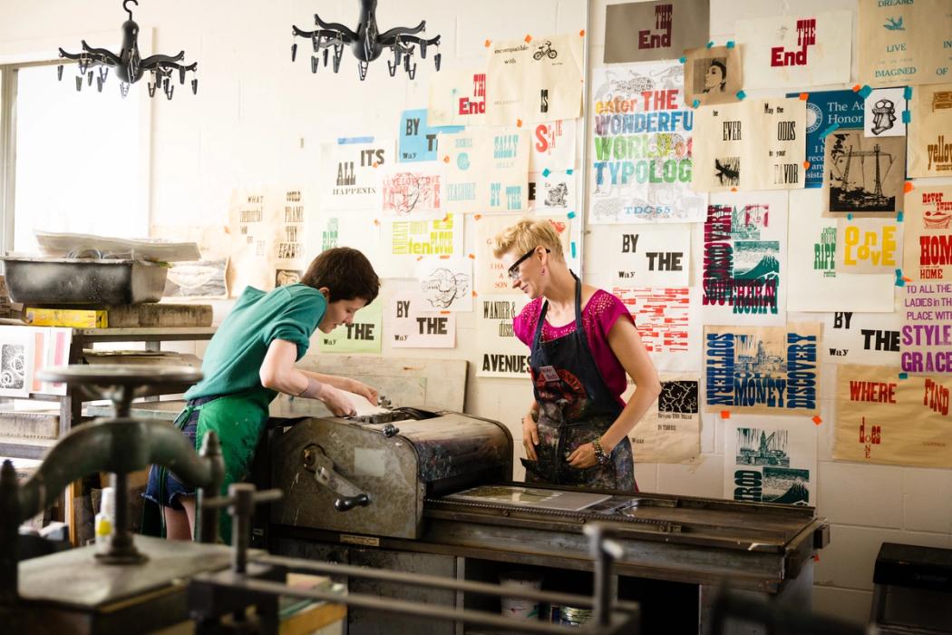 Rachel Simmons teaching letter press techniques on 1950's printing equipment during her art class.