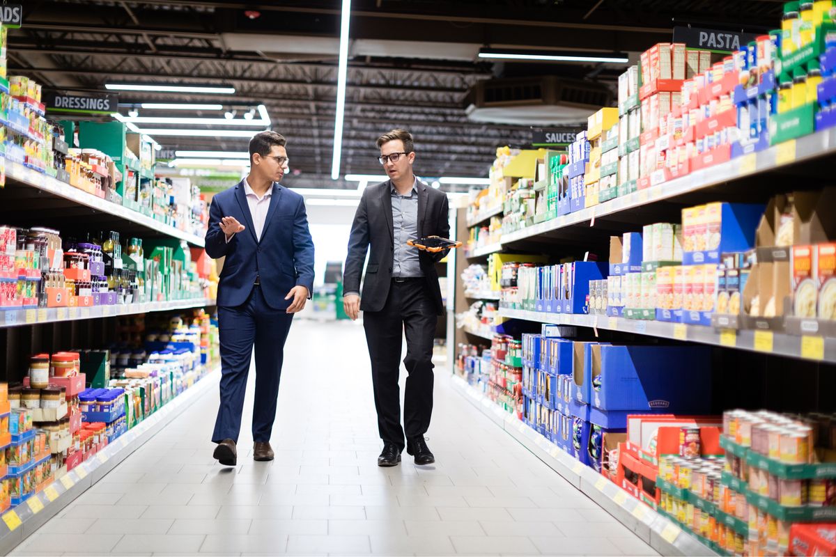 Intern and supervisor walk down the aisle at an ALDI store.