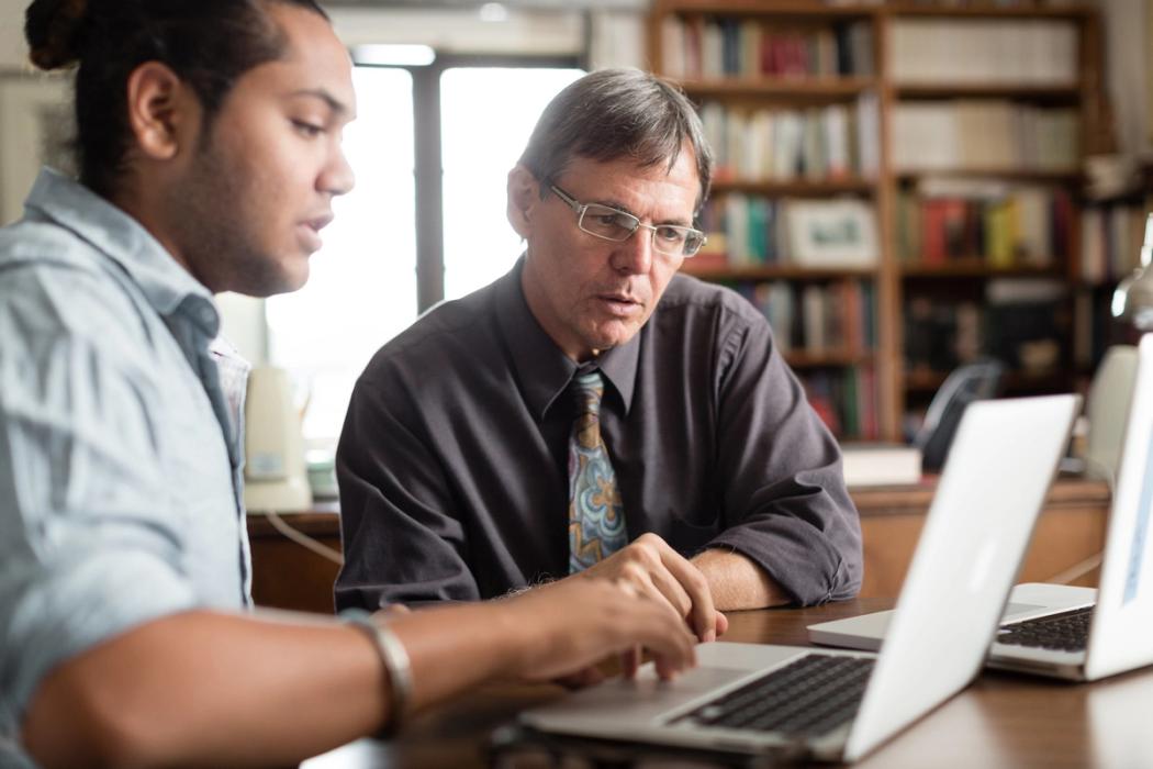 A Rollins professor advises a student on a laptop.