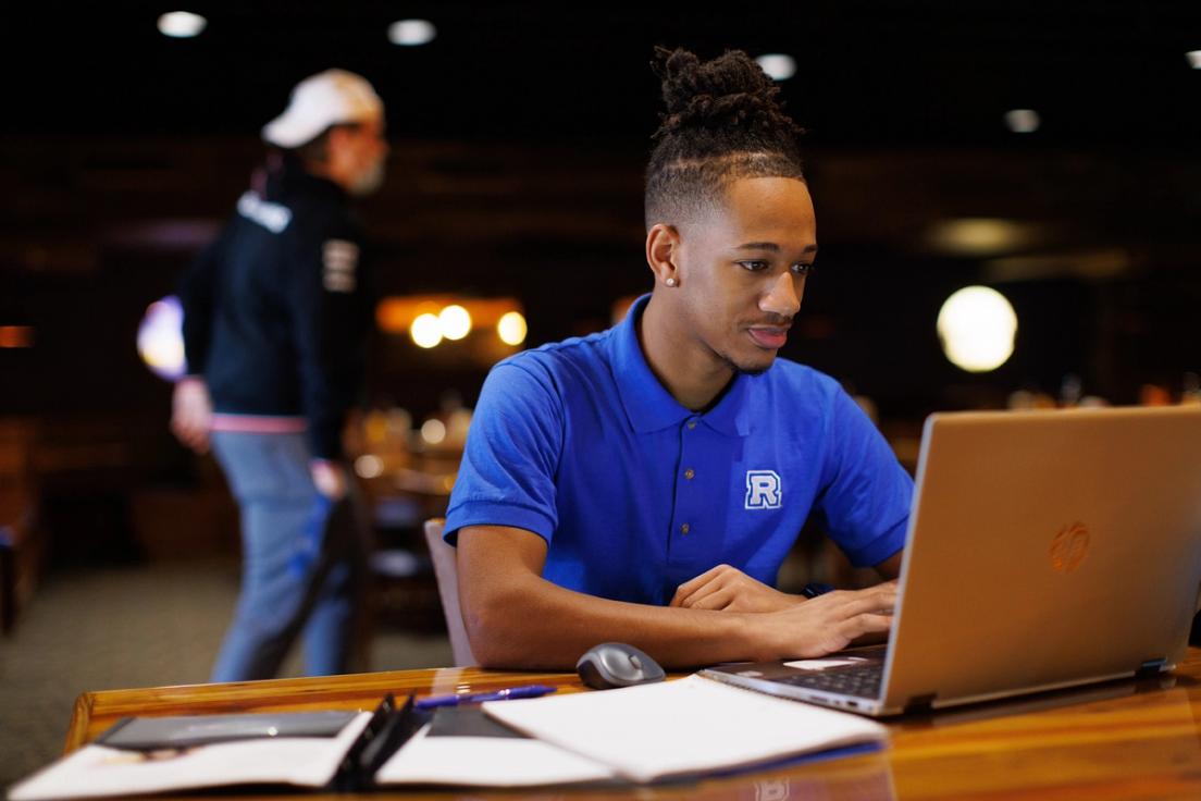 Jaheim Morris ’24 working on his laptop at Dave’s Boathouse on campus at Rollins.