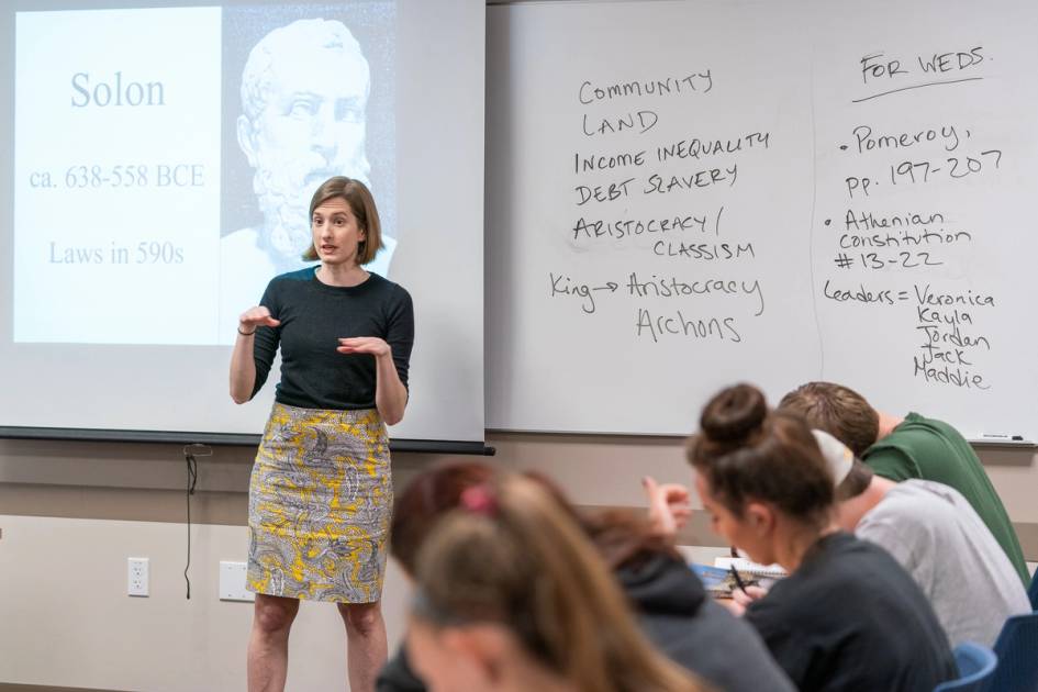 Rollins professor reaching in front of a class