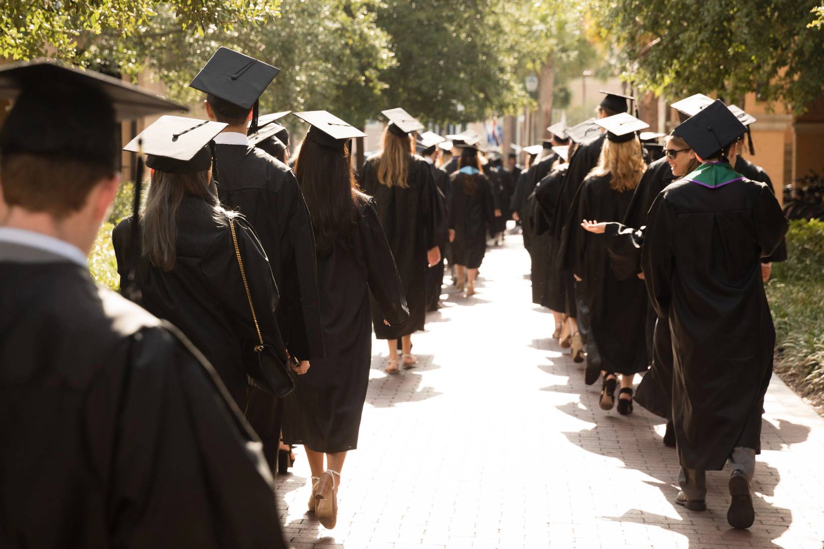 Students in caps and gowns walking to their commencement ceremony.