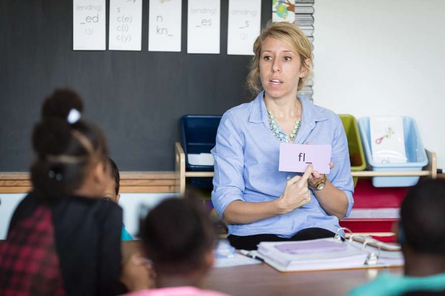 A elementary school teachers points to a flashcard during a lesson.