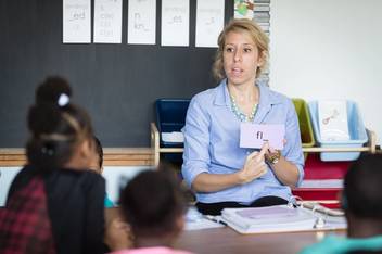 A elementary school teachers points to a flashcard during a lesson.