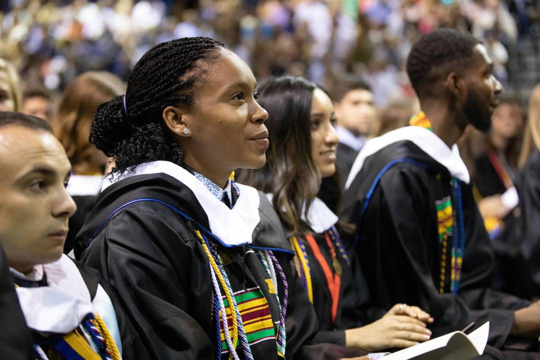 students at Rollins commencement listen to the ceremony, with a happy and proud look on their faces