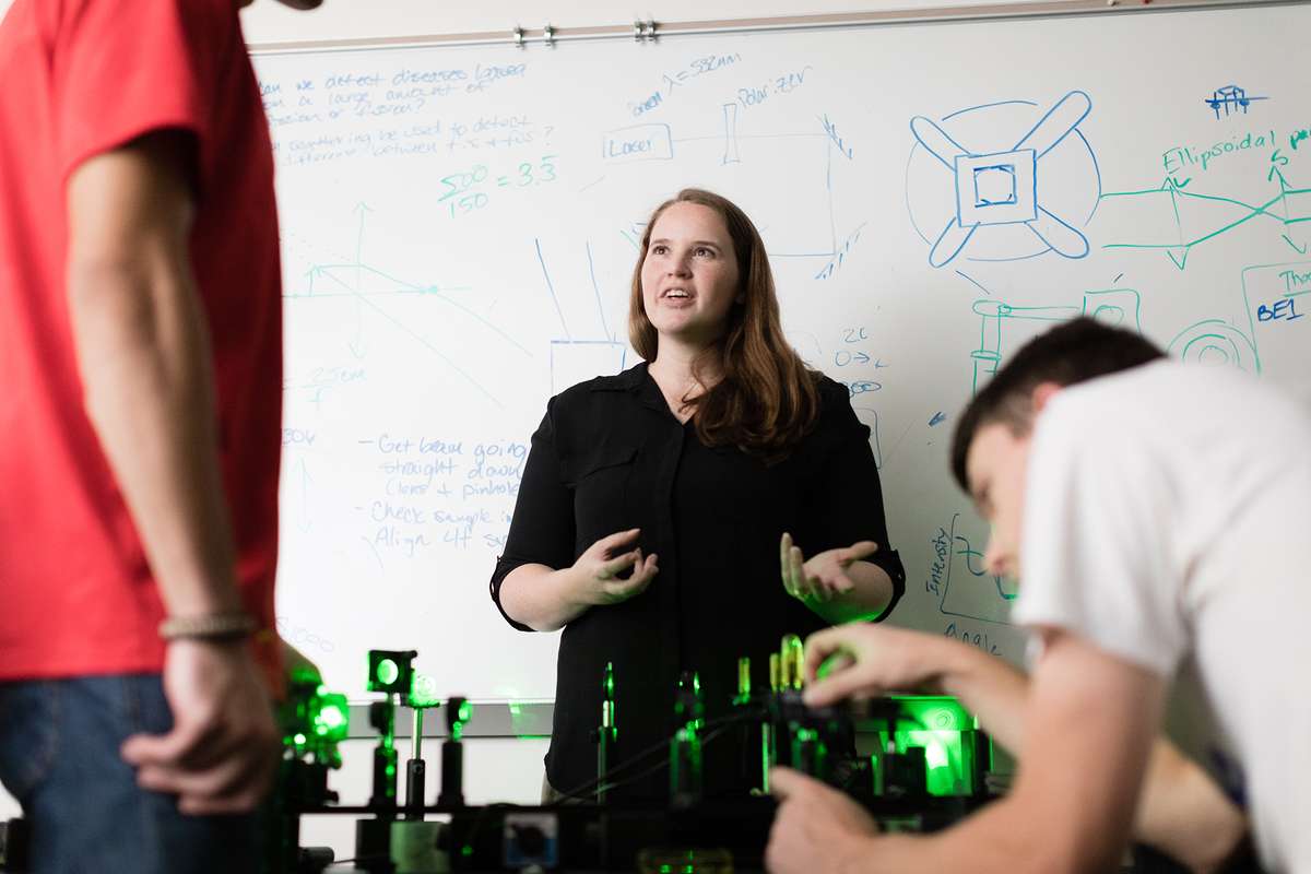 Physics professor working with students on building a microscope.