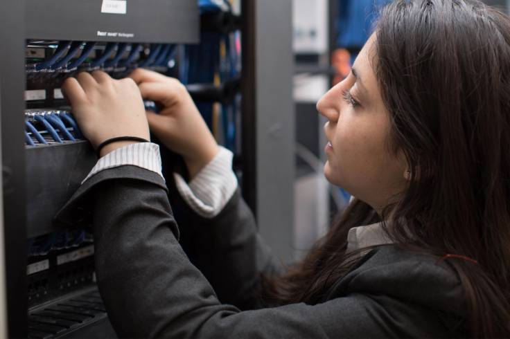 An it student assistant manages cables inside a computer.