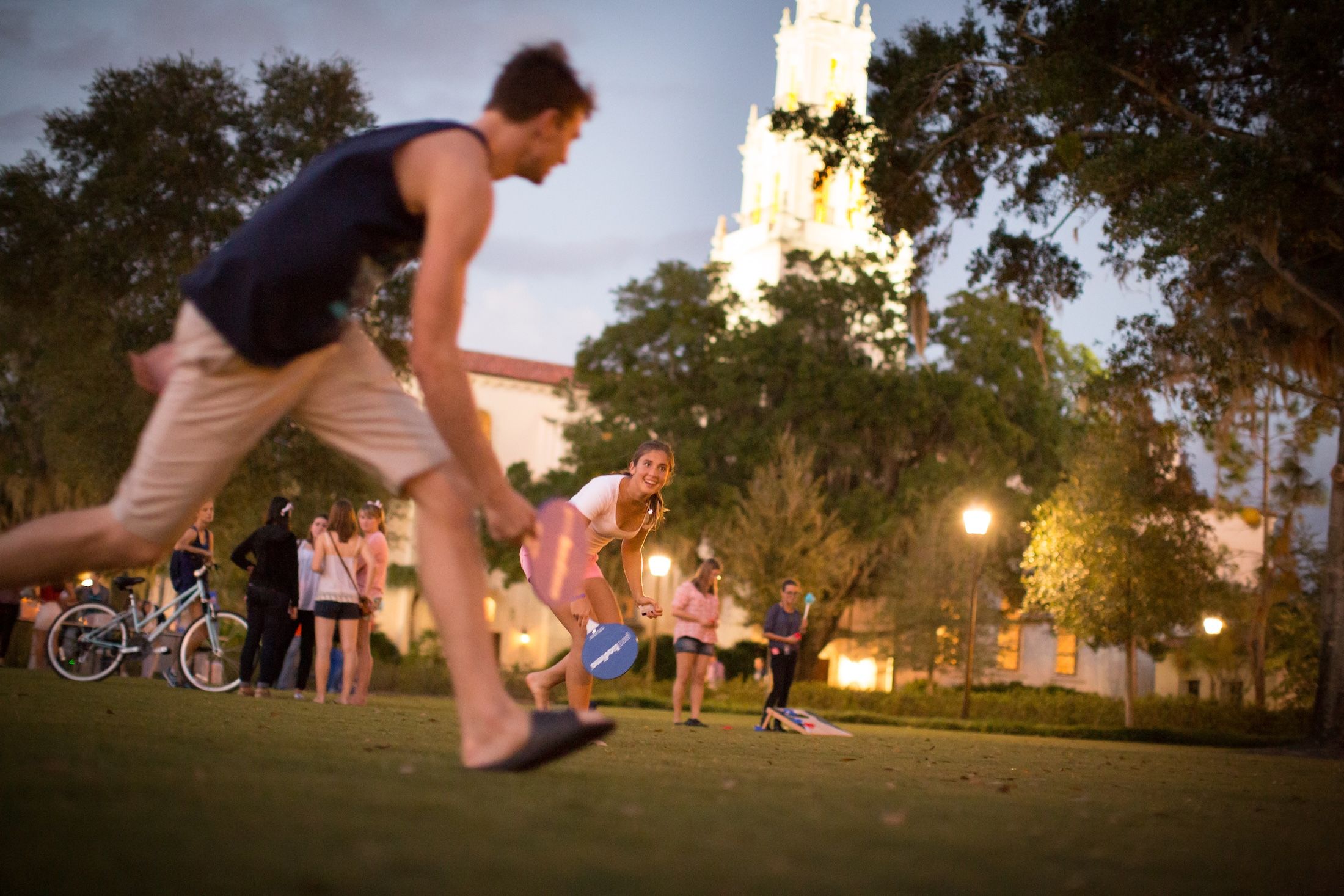 Rollins students play lawn games on Mills Lawn at dusk.