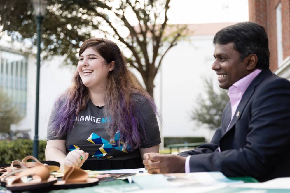 Nikki Hall-Elser sitting with professor Raja Singaram outside at a table.