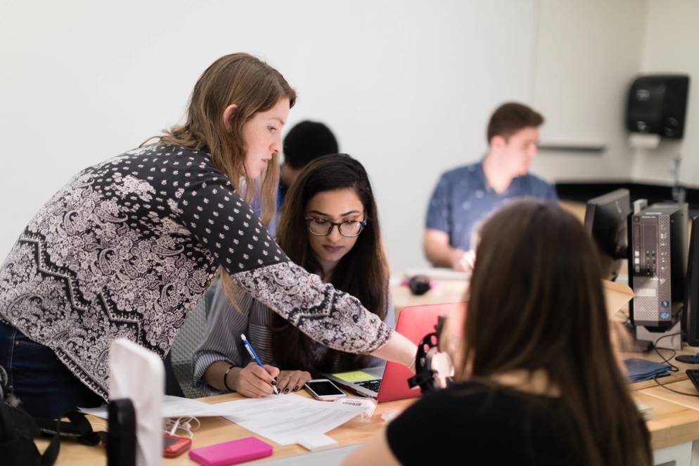 A physics graduate assistant helping students on calculations.