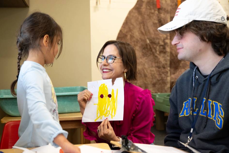 Rollins professor, student, and pre-school child look at a drawing together.